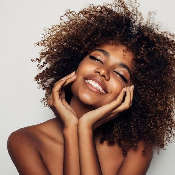 Smiling woman with glowing skin and natural curls